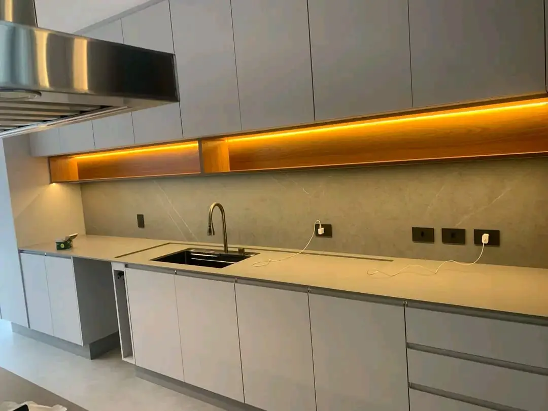 Cozinha planejada cinza com nicho de madeira e fita de LED sobre a bancada